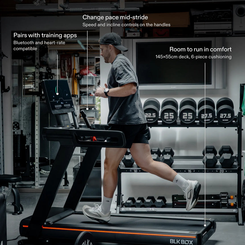 Man running on the BLK BOX 1 Series Treadmill in a home gym: pairs with training apps, speed and incline controls on the handles, 145×55cm cushioned deck