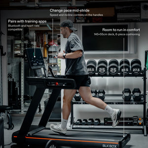 Man running on the BLK BOX 1 Series Treadmill in a home gym: pairs with training apps, speed and incline controls on the handles, 145×55cm cushioned deck